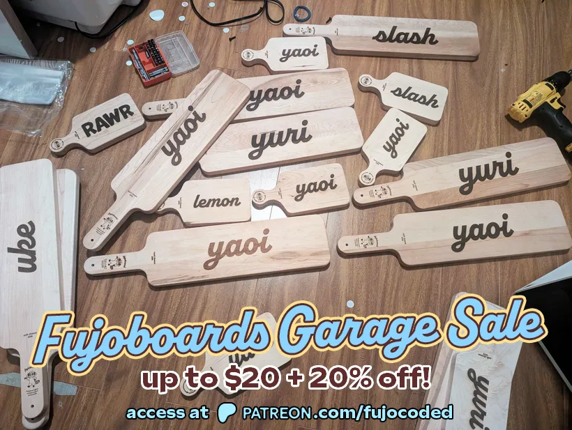 Photograph of a variety of Fujoboards. It is captioned “Fujoboards Garage Sale,
up to $20 + 20% off! Access at Patreon.com/FujoCoded”. Words on the boards are
“Rawr”, “uke”, “lemon”, “yaoi”, “yuri”, and “slash”. Some of the boards are much
smaller. In the background is a drill and bits.